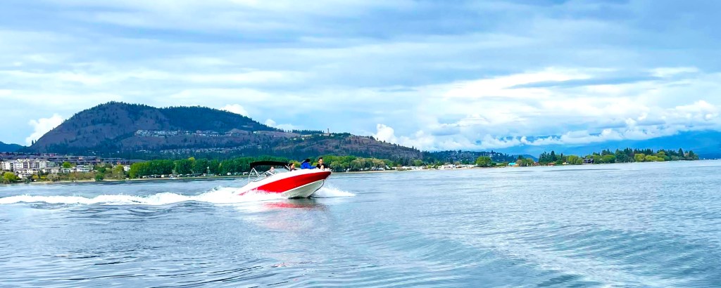 People driving a boat for rent in Kelowna